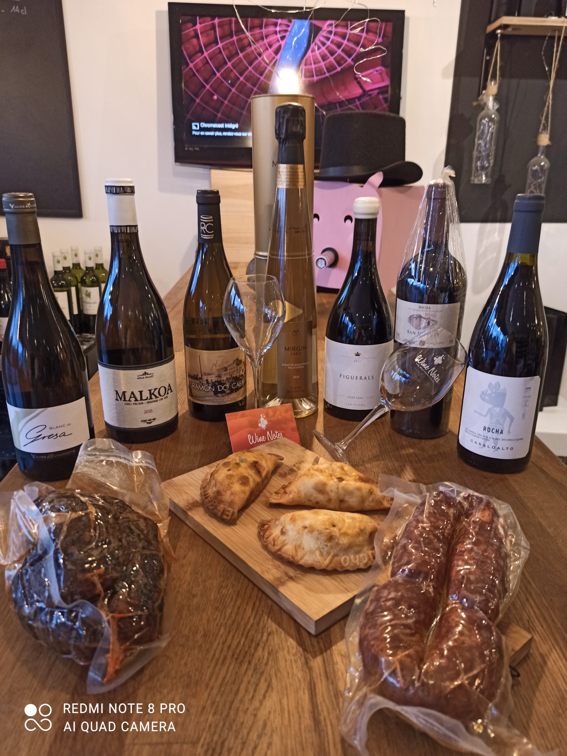 Planche de charcuteries, bouteilles de vins et empanadas disposés sur un table chez le caviste